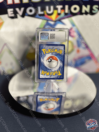 Pokémon card displayed on a reflective surface, featuring a Pokéball and vibrant colors from the Evolutions set.