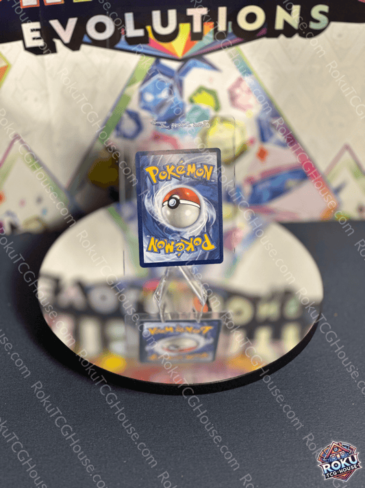 Pikachu EX - Surging Sparks Pokemon card displayed on a reflective surface with colorful background.