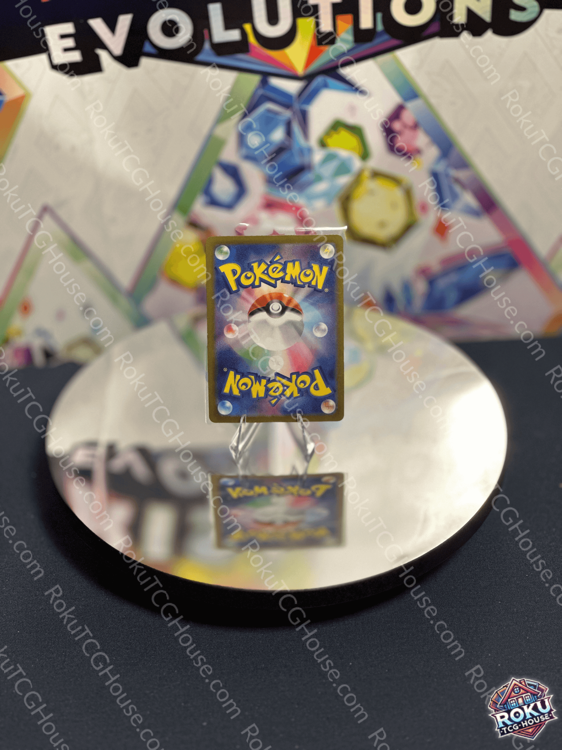 Close-up of a Pokémon card featuring a Pokéball design, displayed on a reflective surface with a colorful background.