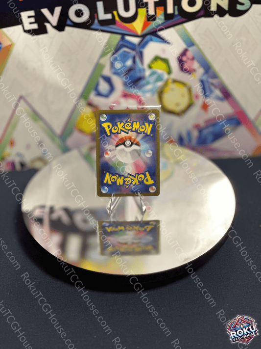Close-up of a Pokémon card featuring a Pokéball design, displayed on a reflective surface with a colorful background.
